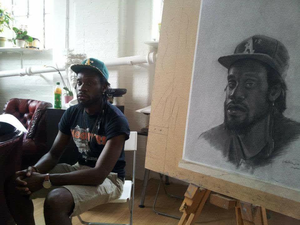 Cristian working beside a graphite portrait in the atelier